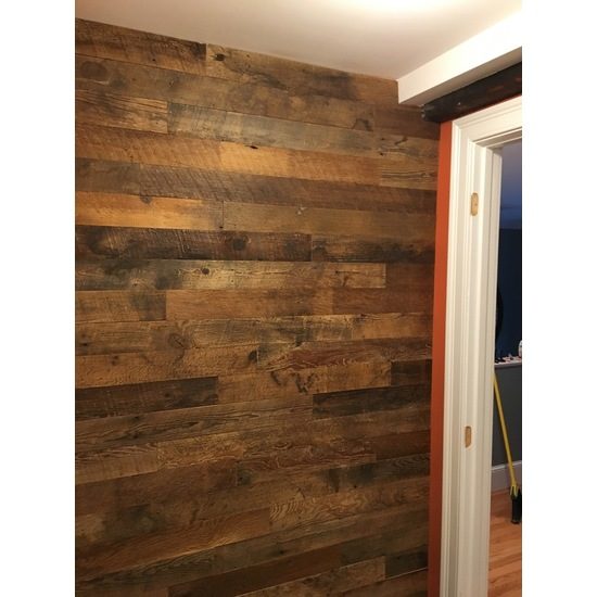 Floor to ceiling wall of brown 3.5 inch reclaimed wood planks in random lengths