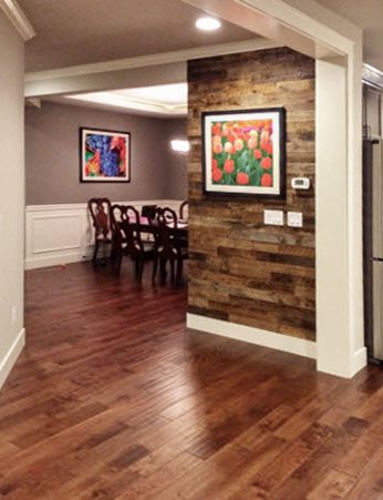 Dining room accent wall of brown reclaimed barn wood planks behind a dining table