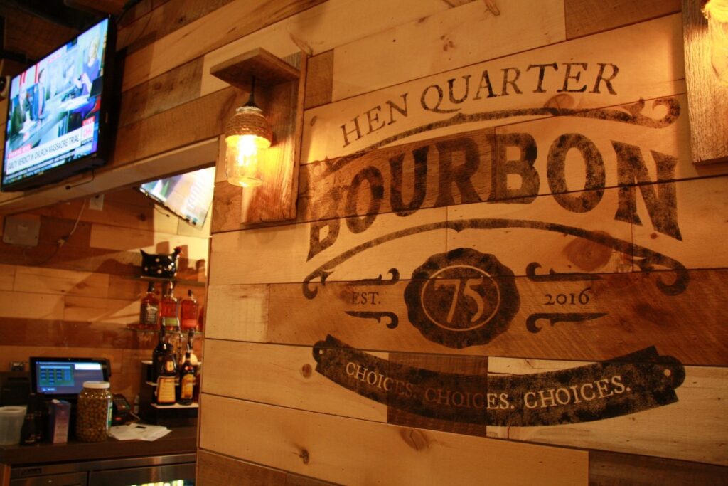Hen Quarter bourbon bar with a brown reclaimed barn wood wall