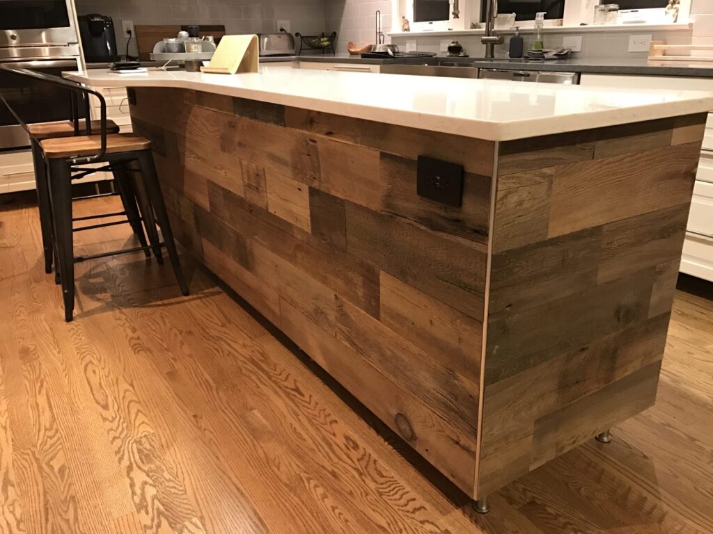 Kitchen island wrapped in brown reclaimed wood planks, a half-height barn wood install