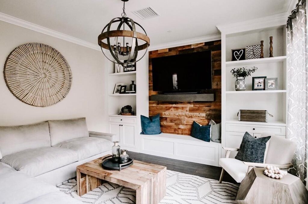 Living room with brown reclaimed wood behind a TV between white built-in shelves