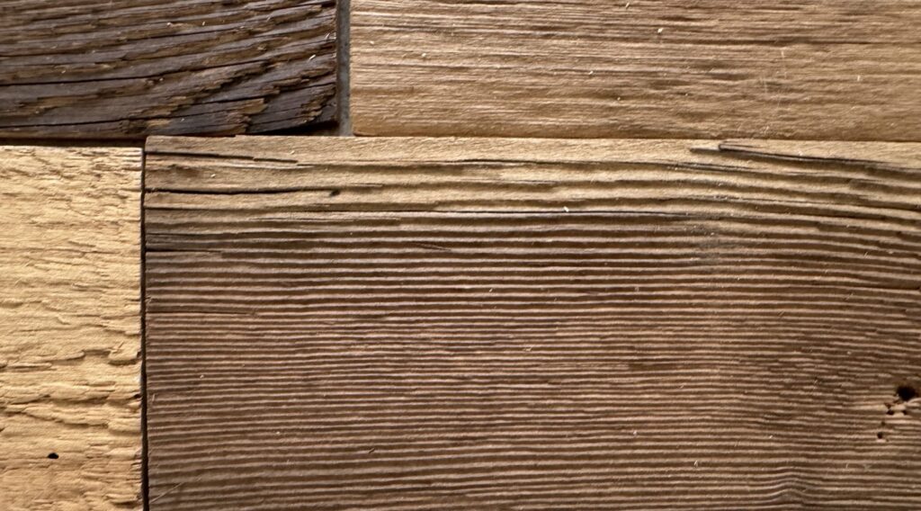 Raking light across reclaimed barn wood showing deep saw kerf texture