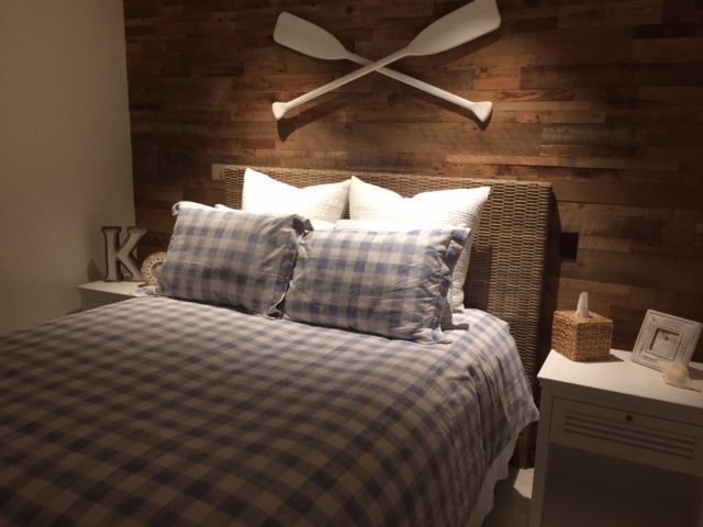 Brown reclaimed wood bedroom wall behind a bed with white and plaid bedding